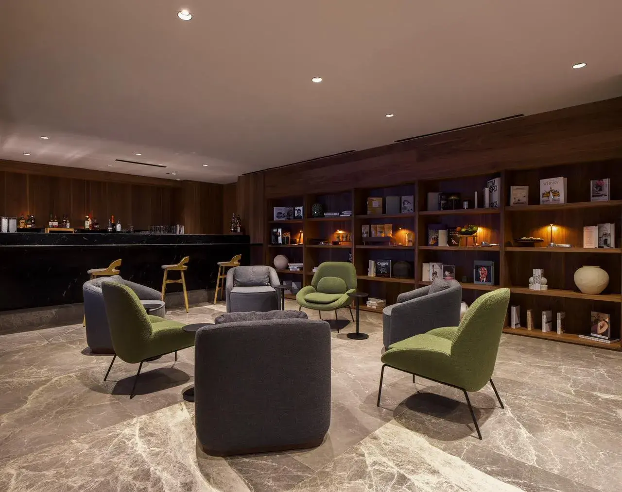 Iluminación ambiental en biblioteca y zona lounge de hotel con estanterías iluminadas de forma indirecta.