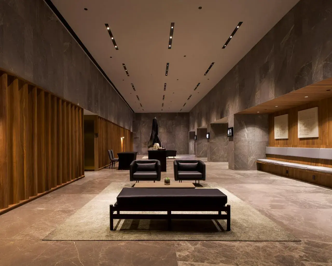 Diseño de iluminación arquitectónica en lobby corporativo de gran altura con luminarias empotradas y acentos cálidos.