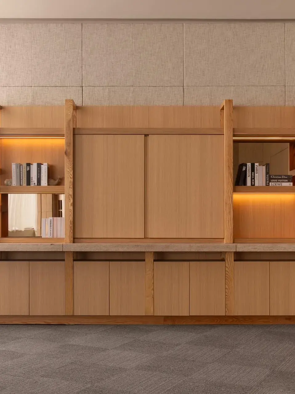 Diseño de iluminación indirecta con tiras LED ocultas en nichos y repisas de un mueble de madera empotrado.