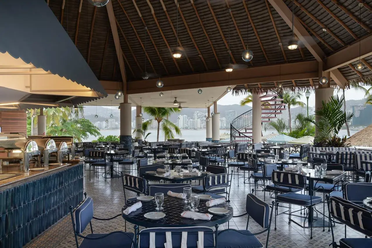 Diseño de iluminación en restaurante abierto con luminarias empotradas en techo de palapa tropical.