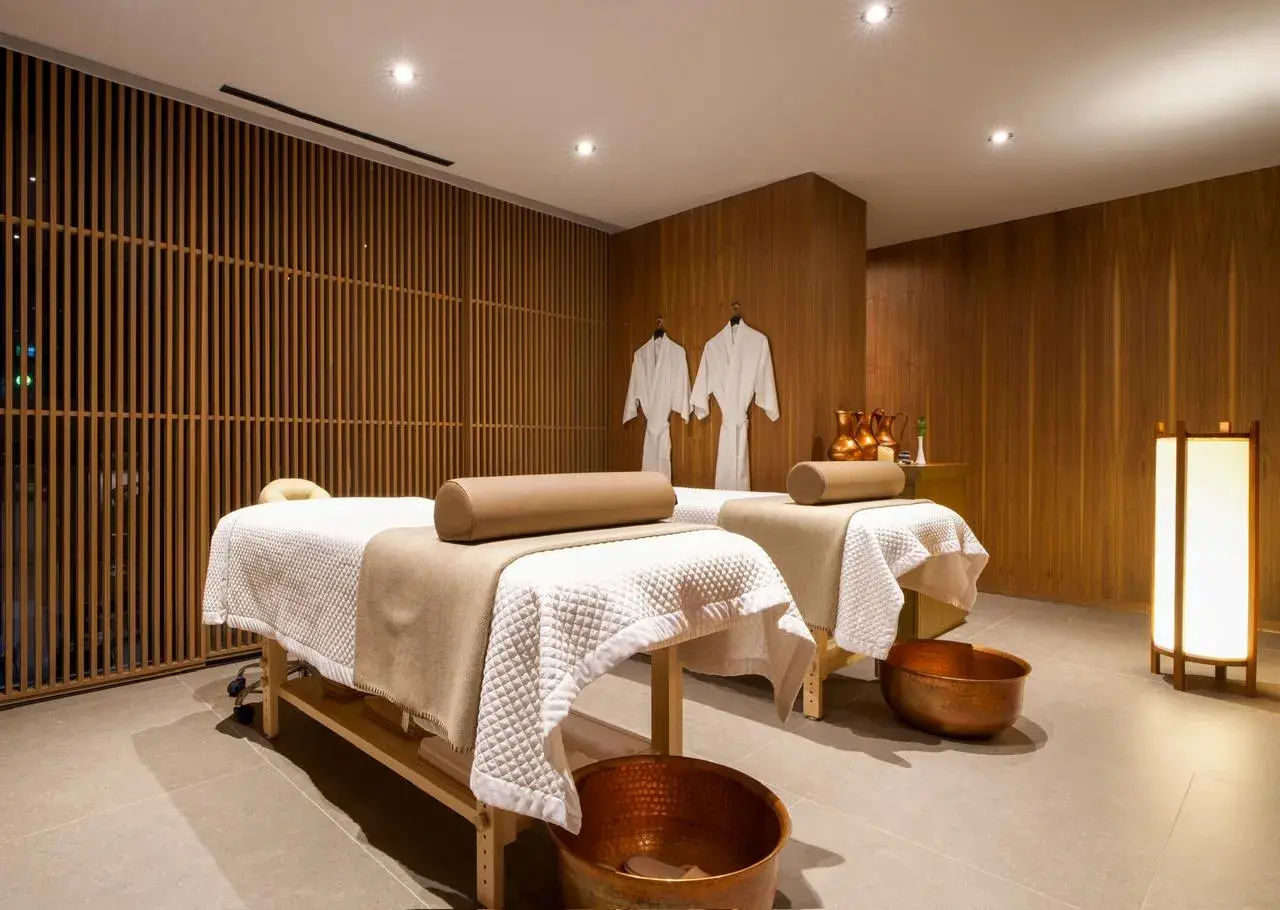Iluminación zen e indirecta en cabina de spa hotelero con acabados de madera y luz tenue para relajación.