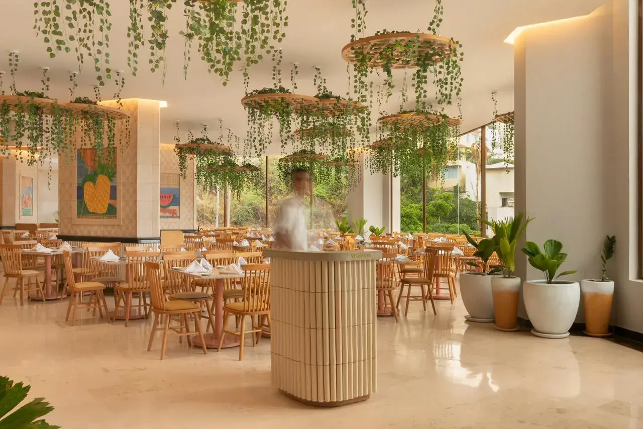 Iluminación integrada con vegetación y plafón con tiras LED en restaurante contemporáneo de tonos claros.